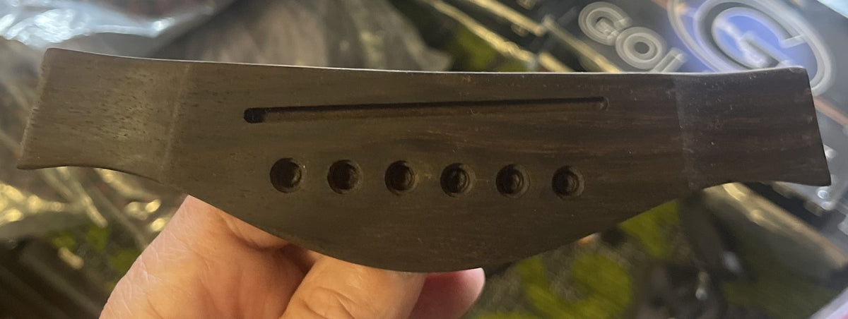 Dark hardwood steel-string acoustic guitar bridge with 6 pin holes and saddle slot
